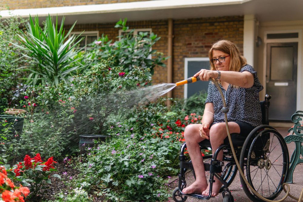 A person using a wheelchair enjoying time outdoors in a garden, representing independence after a disability claim