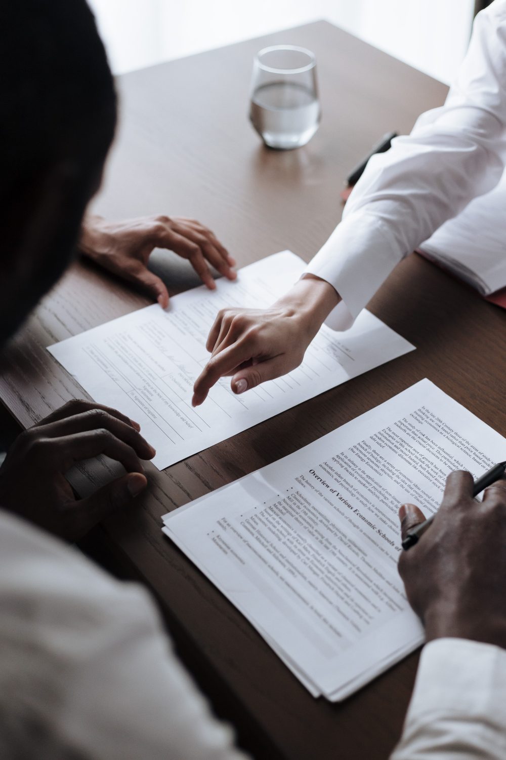 Two people at a desk going through a stack of insurance documents