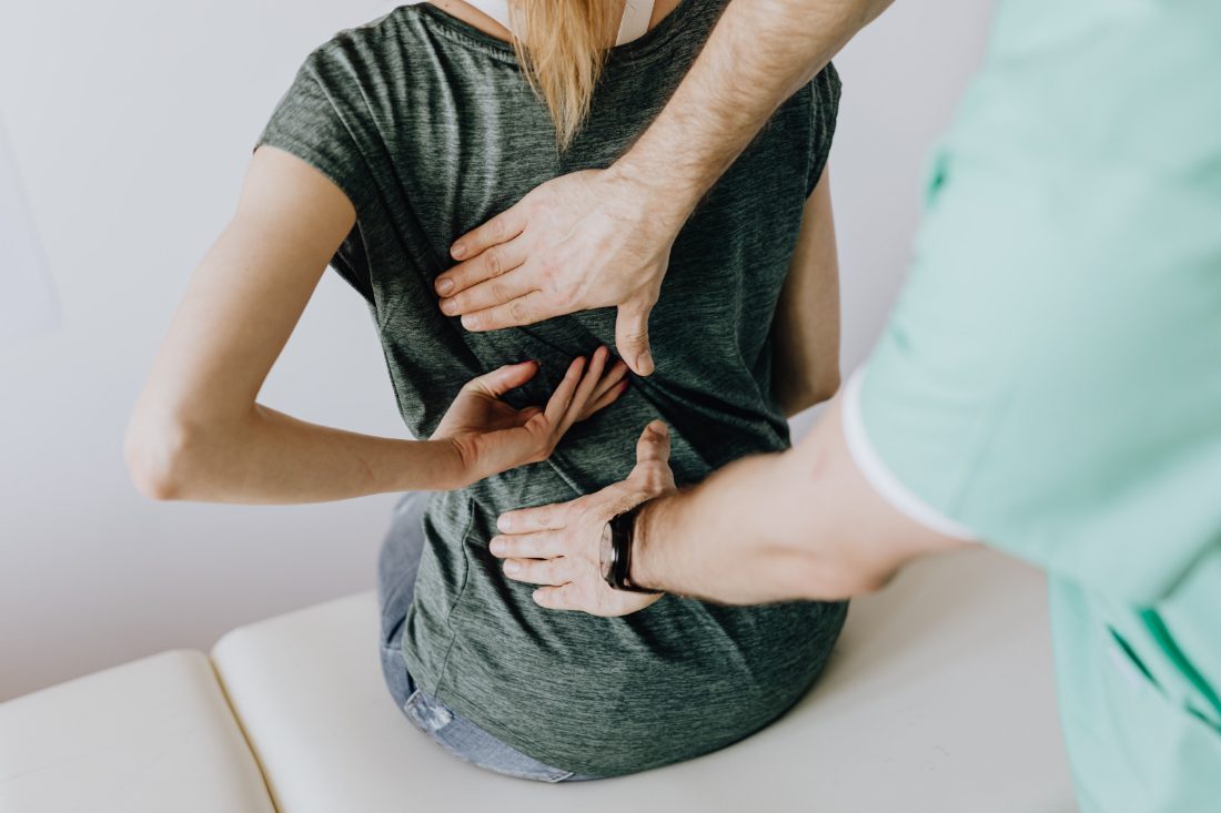 A clinician examining a patient's lower back during a physical exam