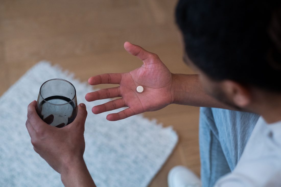 Close-up of a person's open hand holding a single prescription pill