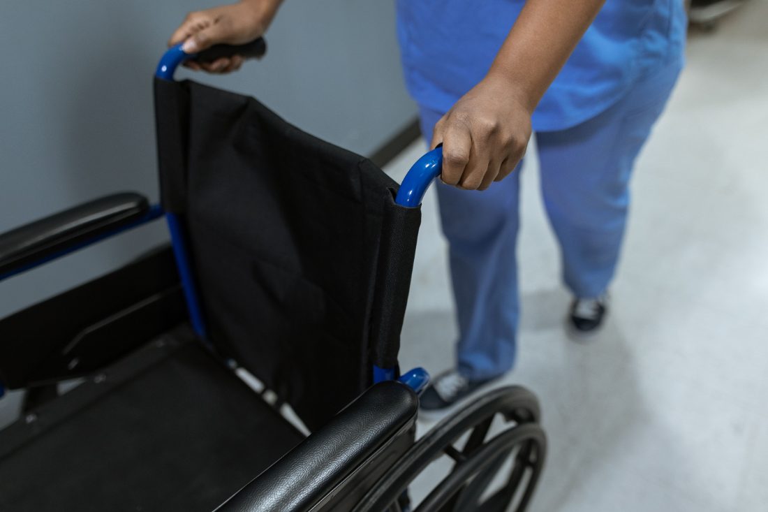 A caregiver walking alongside a person using a wheelchair