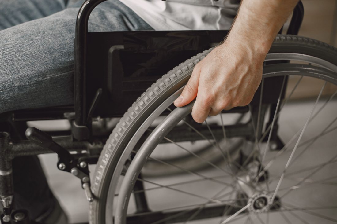 Close-up of a person's hand on the push rim of a wheelchair wheel