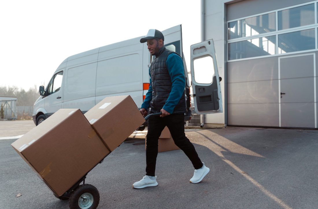 A delivery worker pushing a hand truck stacked with boxes