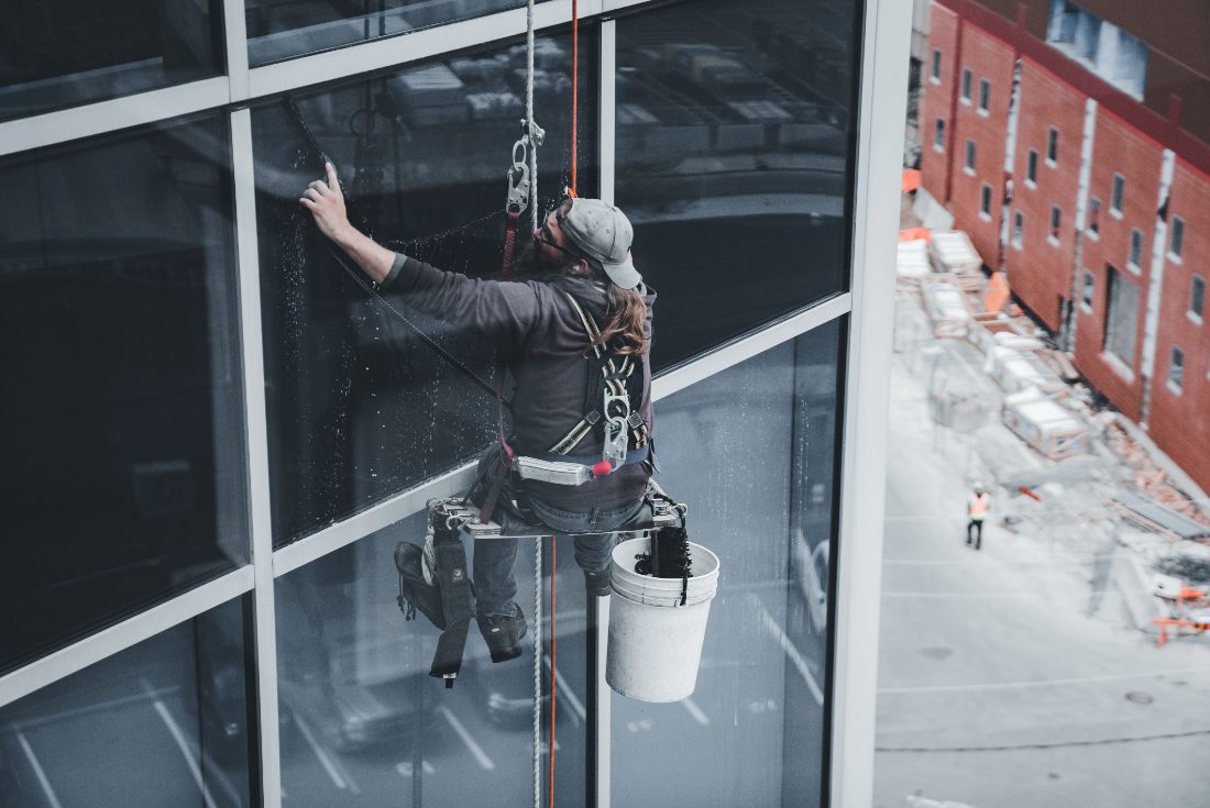 A window washer suspended by ropes while cleaning a high-rise facade